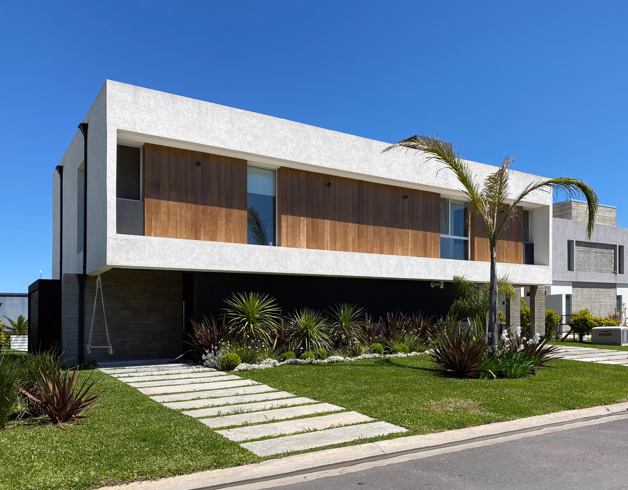 Fachada de Casa SI-199 con volumen superior blanco y basamento de madera